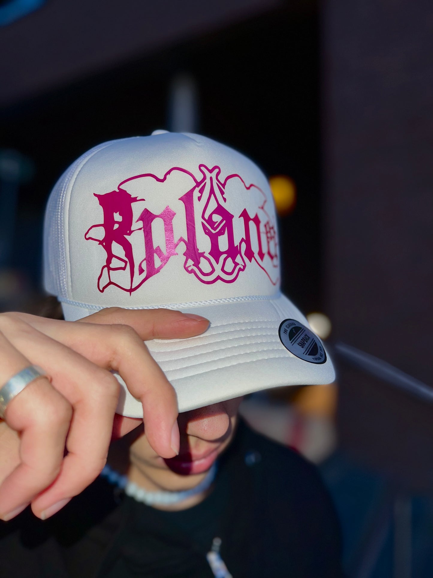White trucker cap with pink logo